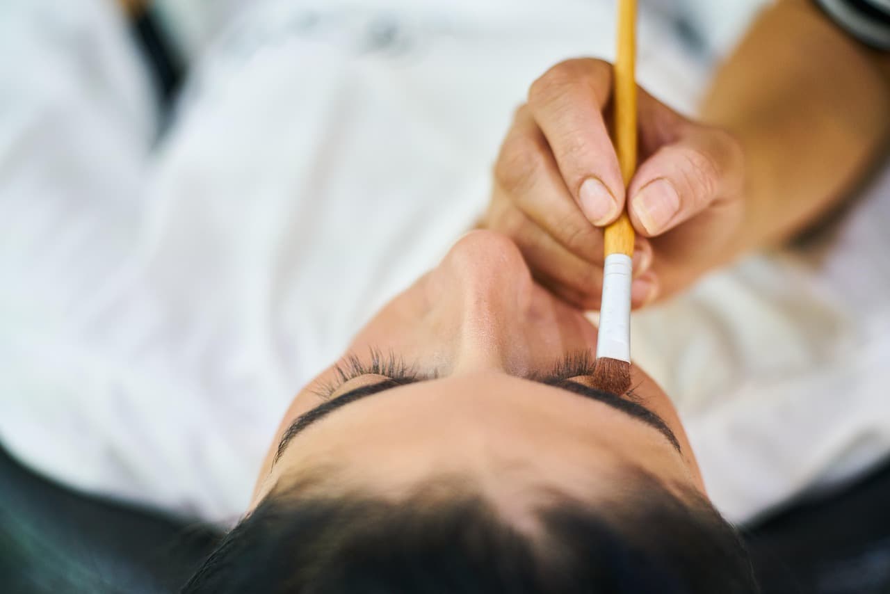 A brow being brushed into shape with a fine brush