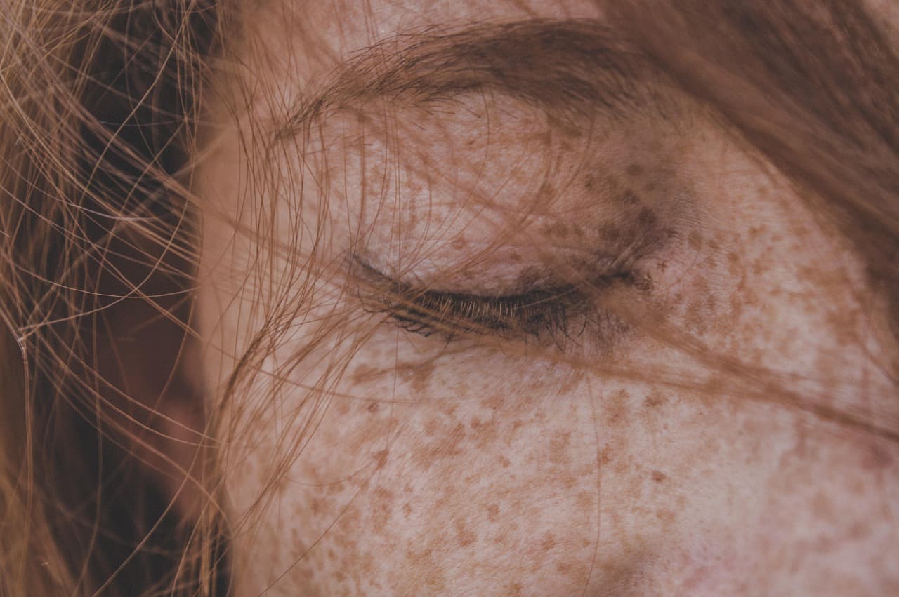 Freckled skin and a soft natural brow in warm light