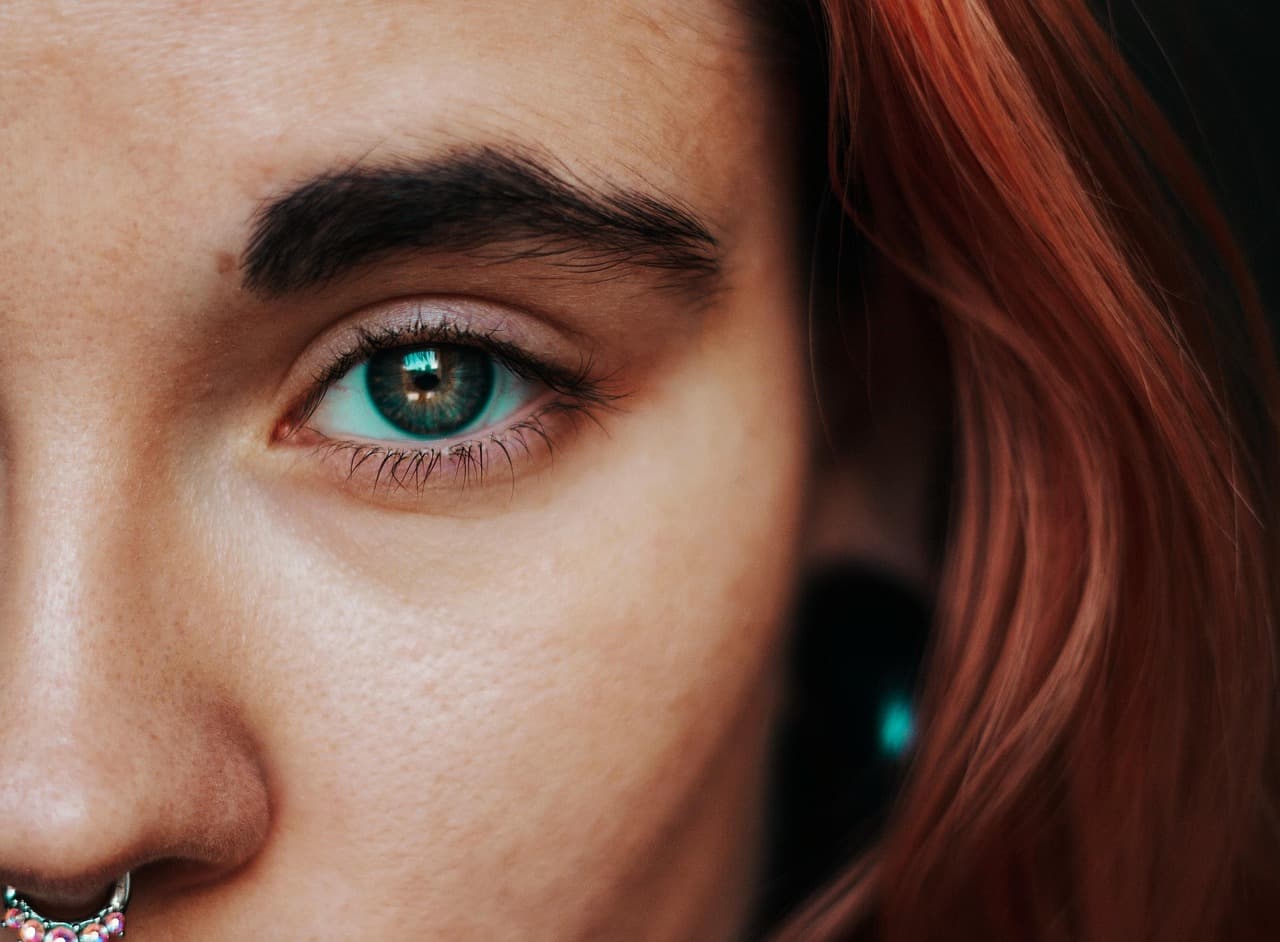 Close-up of a full, dark, natural brow above a green eye